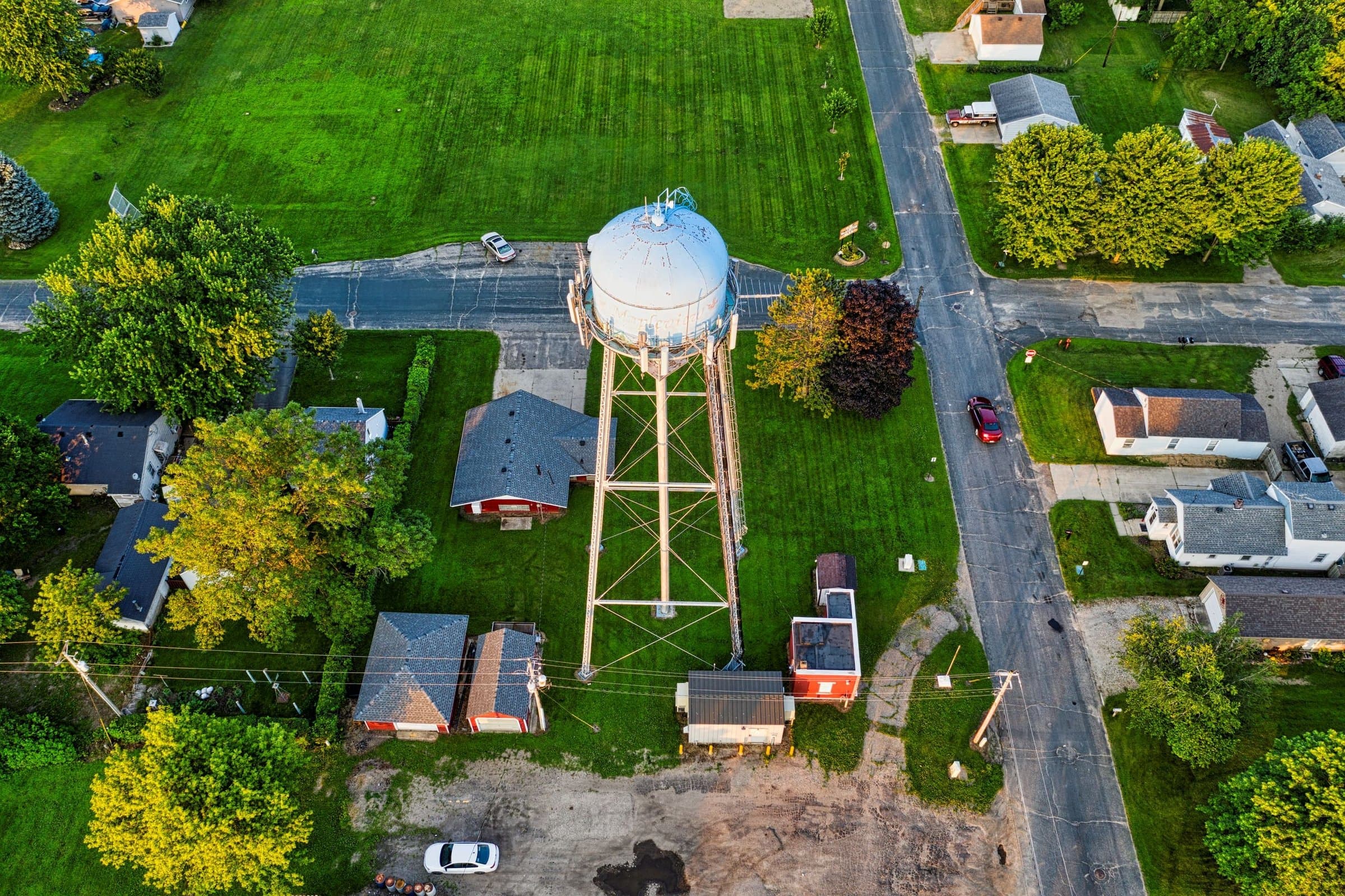Aerial view of a small Midwest town with a water tower and tree-shaded yards